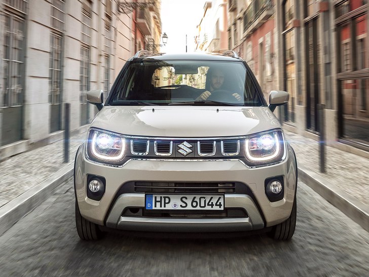 Frontansicht des Suzuki Ignis Hybrid in Caravan Ivory Perl Metallic mit eingeschaltetem Licht.