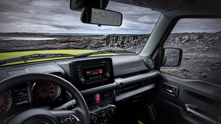 Aufnahme des Innnenraums eines Suzuki Jimny Hybrid in Kinetic Yellow, im Hintergrund eine Felsenlandschaft.