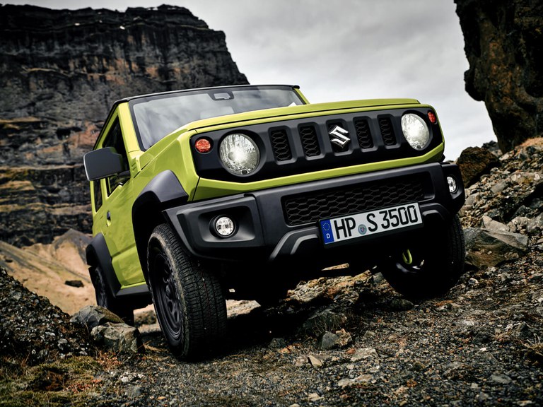 Suzuki Jimny Hybrid in Kinetic Yellow steht auf einem Geröllhang.