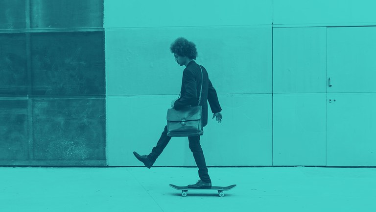 Ein junger Mann fährt auf einem Skateboard von rechts nach links. Vor dem Bild ist ein hellblauer Filter.